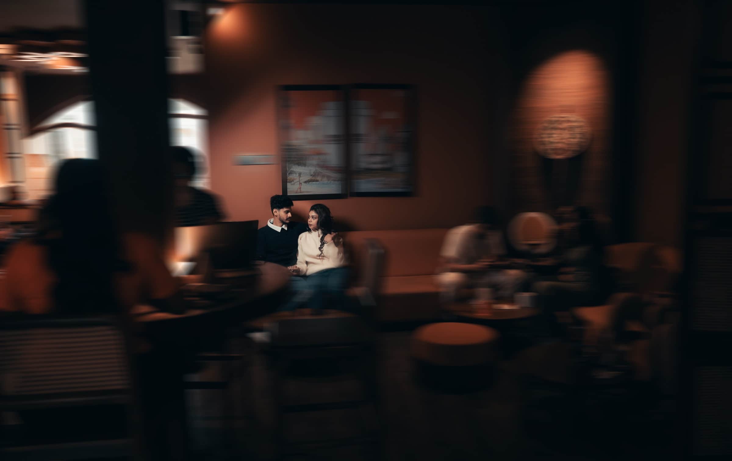 A couple in a warm, dimly lit lounge captured through a soft motion-blurred frame